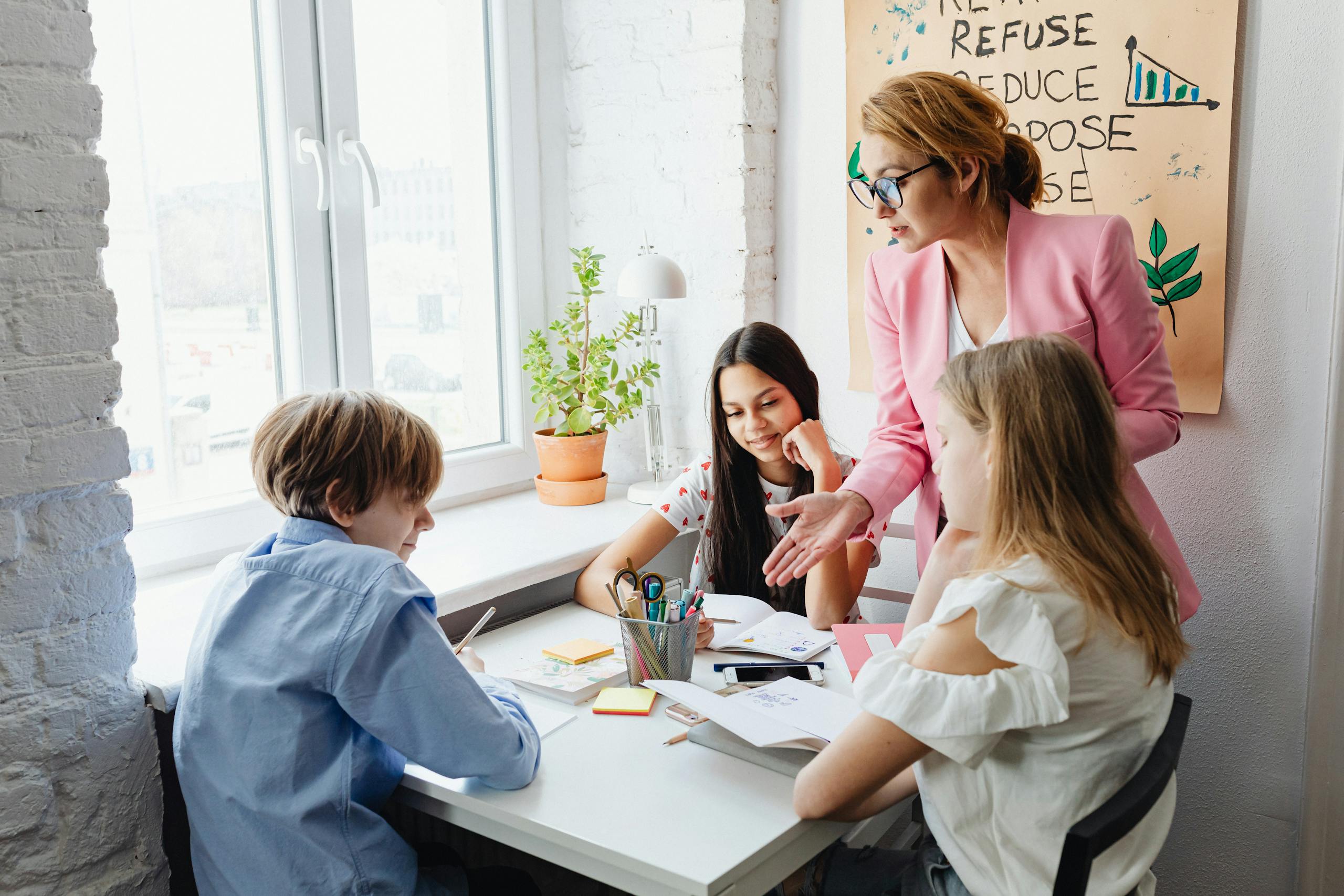 A female teacher instructs a diverse group of teenagers in a sunlit classroom, promoting engagement and learning.