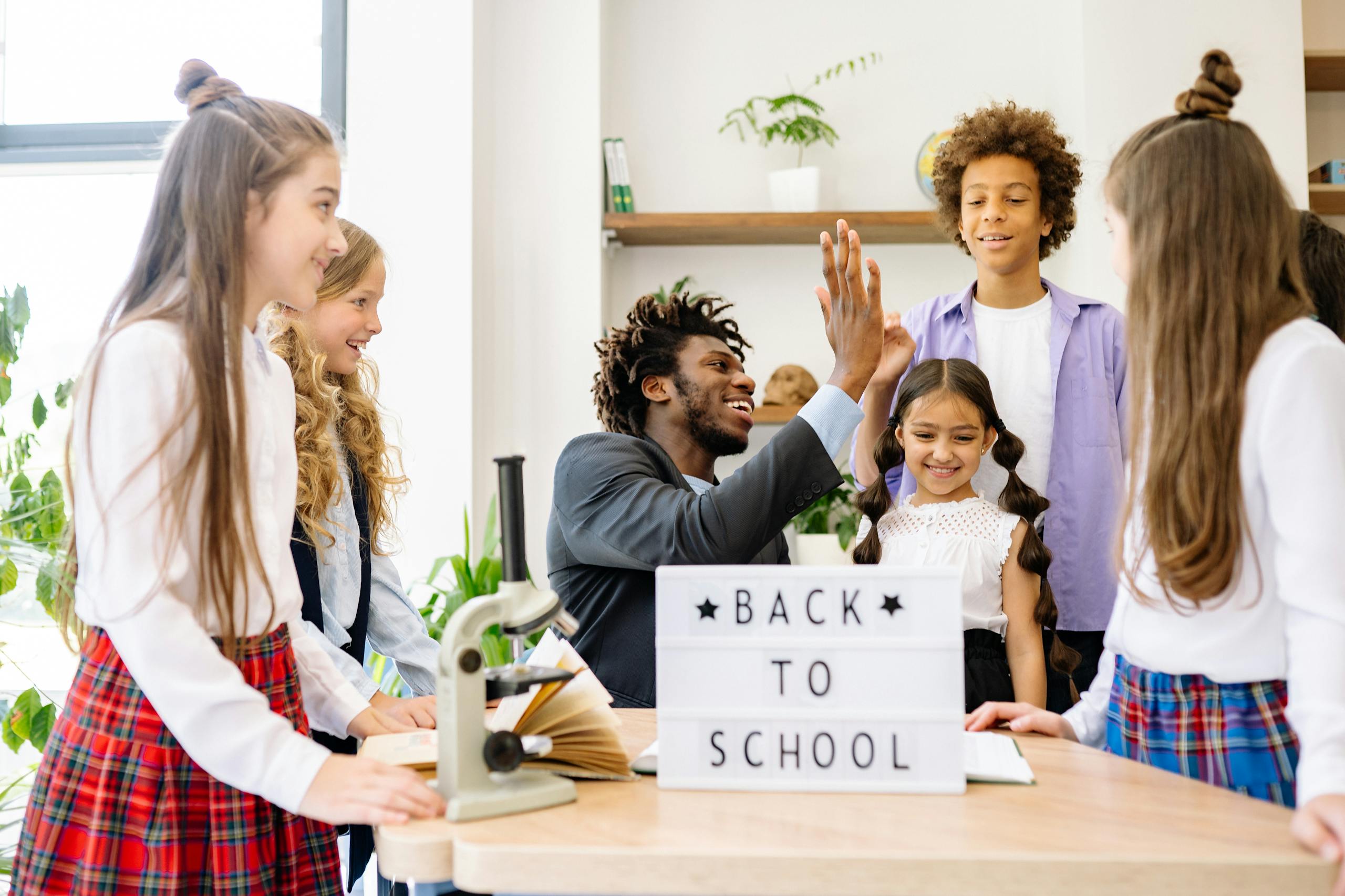 Happy students with a teacher celebrating 'Back to School' indoors.